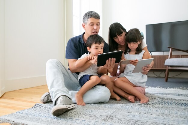 タブレットコンピューターとスマートフォンを使用して幸せな家族の肖像画。