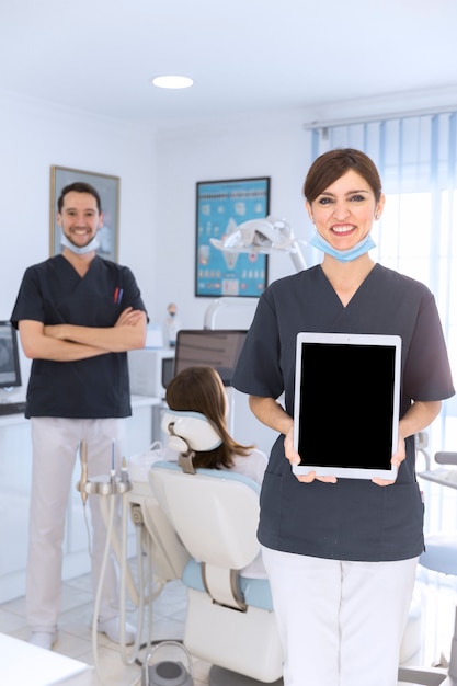 デジタルタブレットをクリニックで見せる幸せな女性の歯科医の肖像