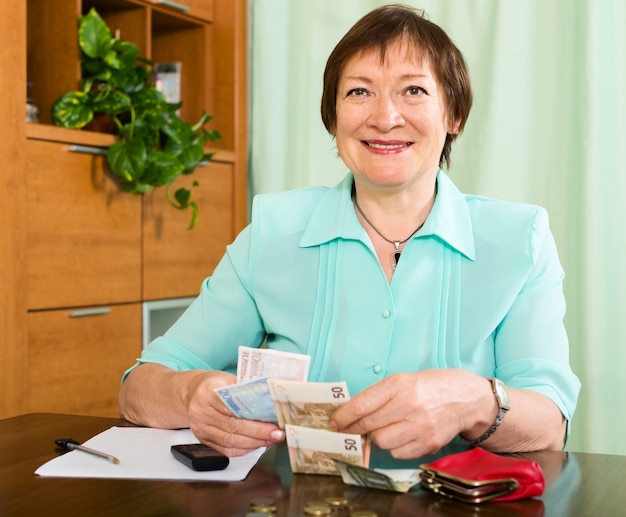 Ritratto di felice pensionato femminile con contanti e fatture