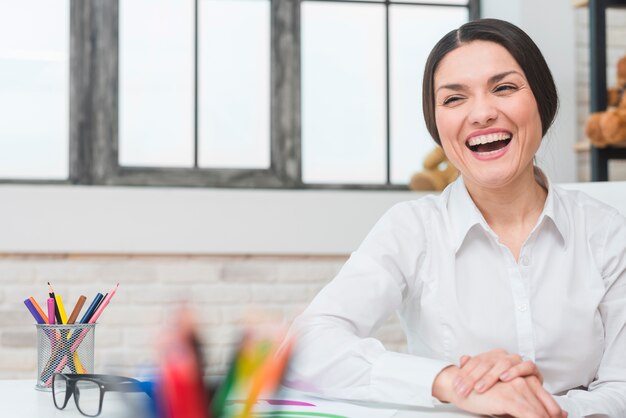 Portrait of happy female psychologist laughing in the office