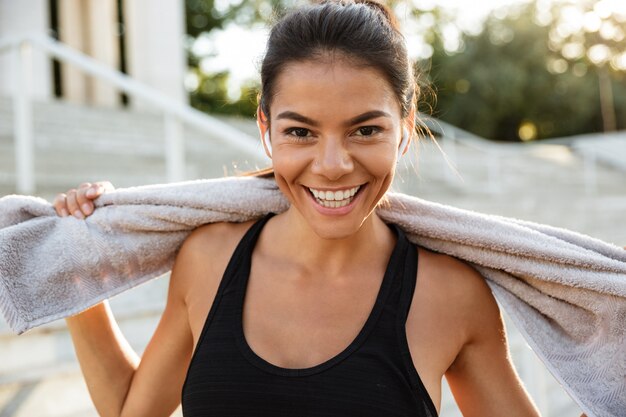 Portrait of a happy fitness woman with towel resting