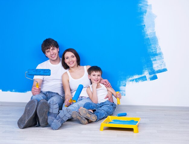 Portrait of happy friendly family sitting on the floor with paintbrush