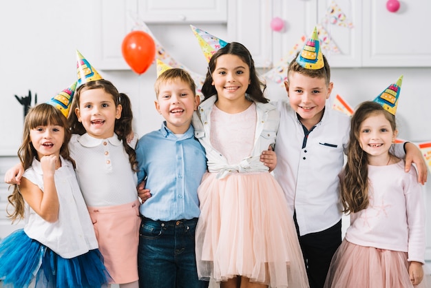 Portrait of happy friends wearing party hat standing together