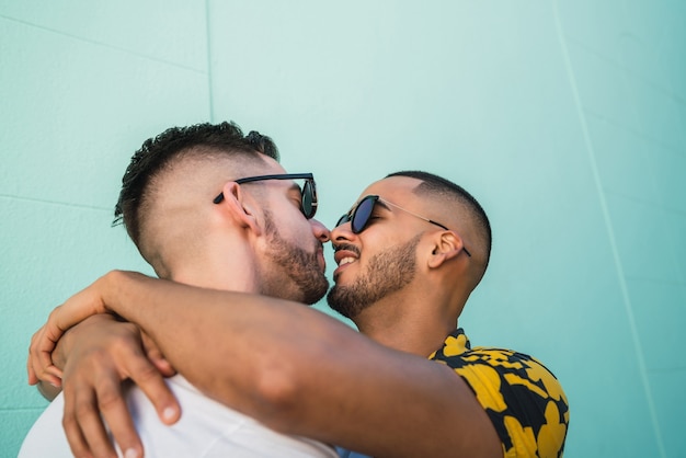 Portrait of happy gay couple hugging and kissing in the street. Lgbt and love concept.