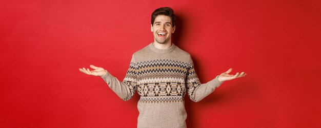 Portrait of happy goodlooking man celebrating new year holidays wearing christmas sweater spread han