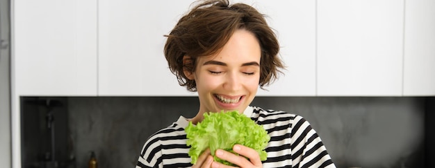 Free photo portrait of happy and healthy young woman following her diet posing with lettuce leaf and smiling