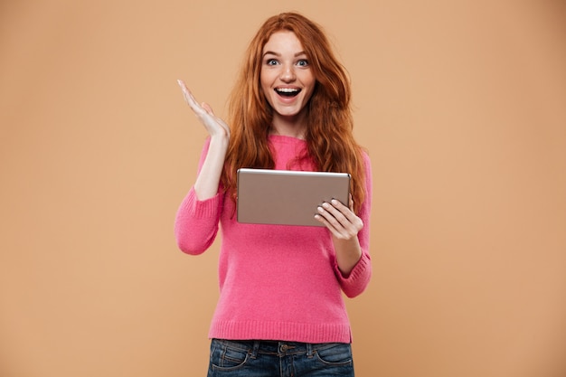 Portrait of a happy joyful redhead girl holding tablet