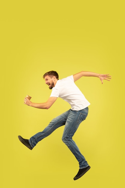 Portrait of happy jumping man on yellow wall