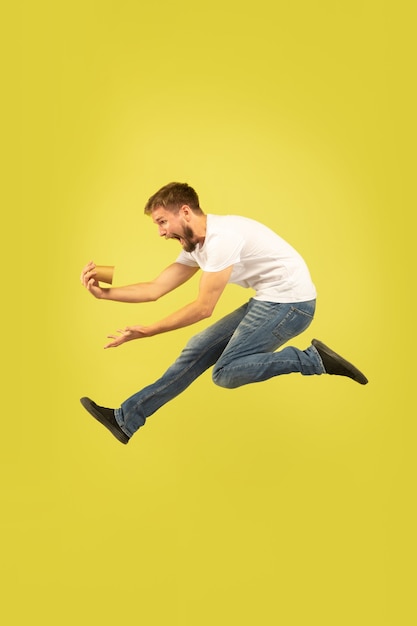 Portrait of happy jumping man on yellow wall