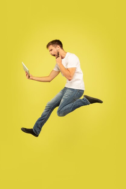 Portrait of happy jumping man on yellow wall