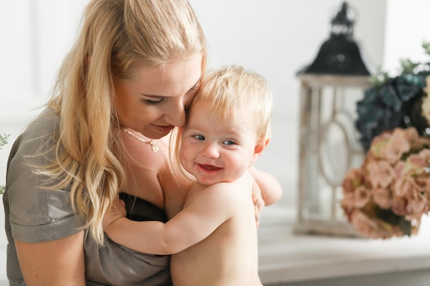 Portrait of happy laughing baby hugging with cheerful young smiling mother. 