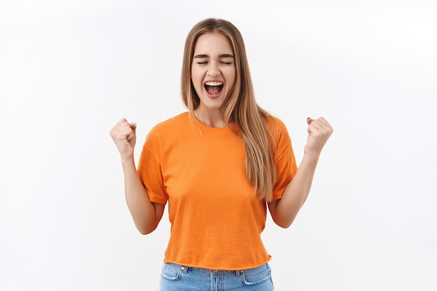 Portrait of happy, lucky girl winner, celebrating success, close eyes and smiling delighted