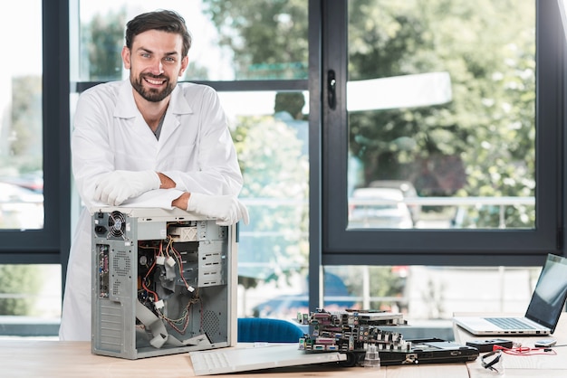 Portrait of a happy male technician with broken computer