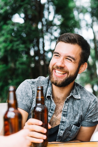 Портрет счастливый человек, проведение коричневый бутылку пива в руке