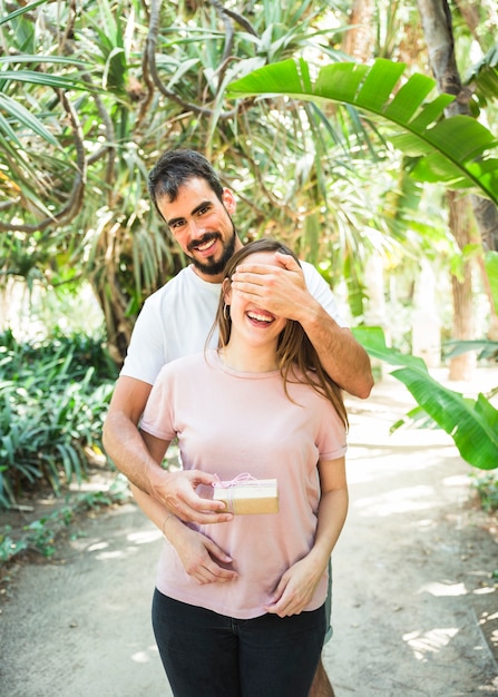 Foto gratuita ritratto di un uomo felice che fa sorpresa con regalo per la sua ragazza nella foresta