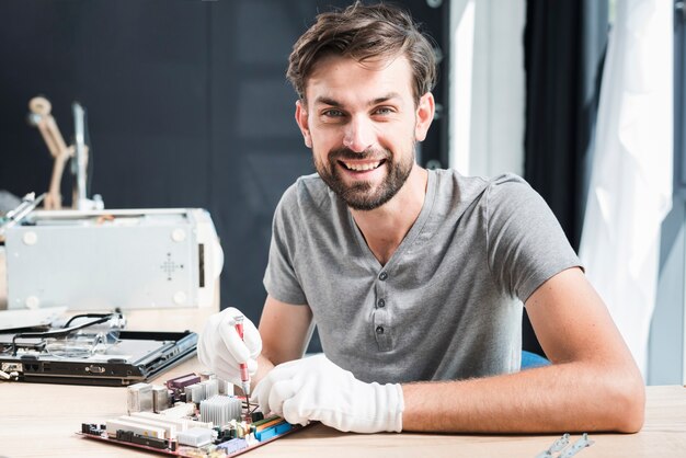 Portrait of a happy man repairing circuit board of computer