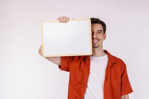 격리 된 흰색 배경에 빈 간판을 보여주는 행복 한 남자의 초상화