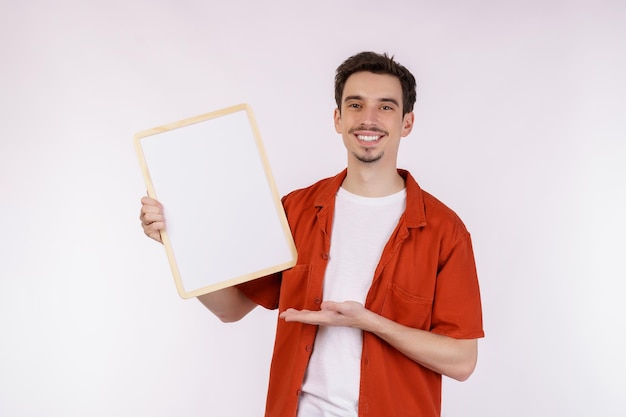 격리 된 흰색 배경에 빈 간판을 보여주는 행복 한 남자의 초상화