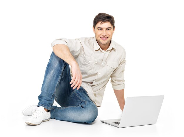 白で隔離のカジュアルなノートパソコンで作業している幸せな男の肖像画。