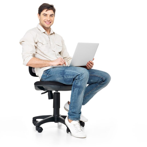 ノートパソコンで作業している幸せな男の肖像画が椅子に座っています