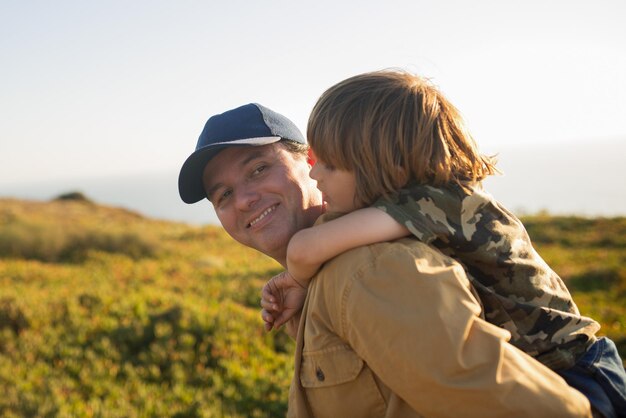 Portrait of happy mid adult man carrying son