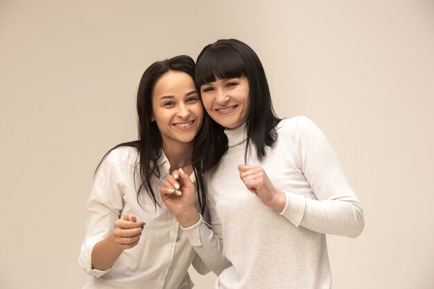 A portrait of a happy mother and daughter on gray