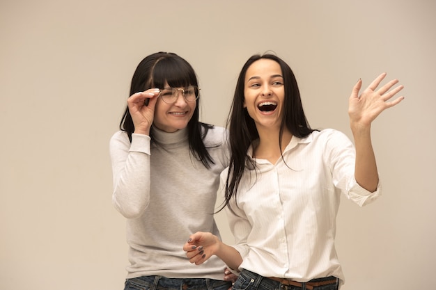 Free photo a portrait of a happy mother and daughter at studio on gray background. human positive emotions and facial expressions concept