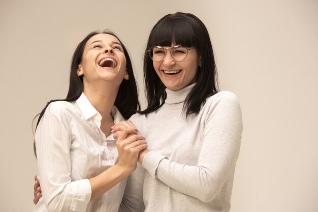A portrait of a happy mother and daughter at studio on gray