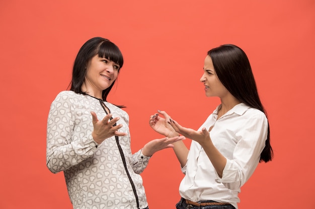 portrait of a happy mother and daughter at studio on living coral background. Trendy colors. Human positive emotions and facial expressions concept