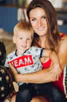 Free photo portrait of happy mother and son posing together mom hugging her child beautiful woman and cute son looking at camera and smiling pretty kid having blonde hair