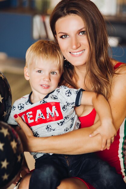 Portrait of happy mother and son posing together mom hugging her child Beautiful woman and cute son looking at camera and smiling Pretty kid having blonde hair