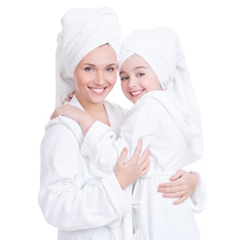 Portrait of happy mother and young daughter in white dressing gown and towel- isolated. happy family people concept.