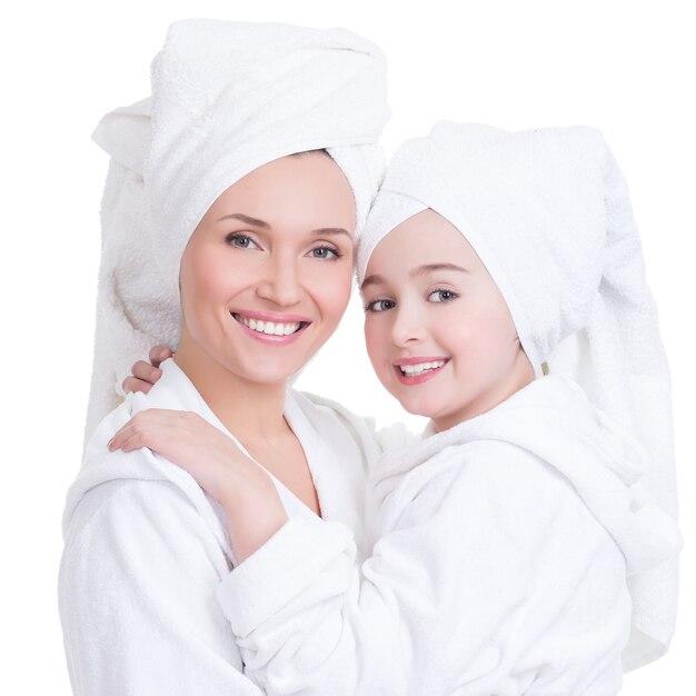 Portrait of happy mother and young daughter in white dressing gown and towel- isolated