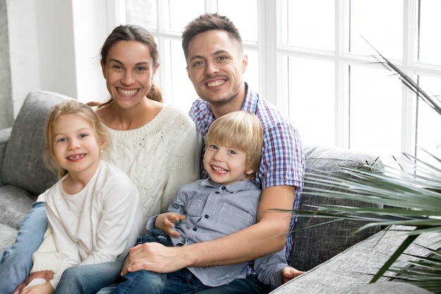 Portrait of happy multi-ethnic family embracing adopted kids bonding together