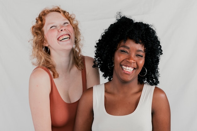Portrait of happy multi ethnic female friends against grey backdrop