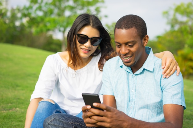 Portrait of happy multiethnic couple networking on smartphone.