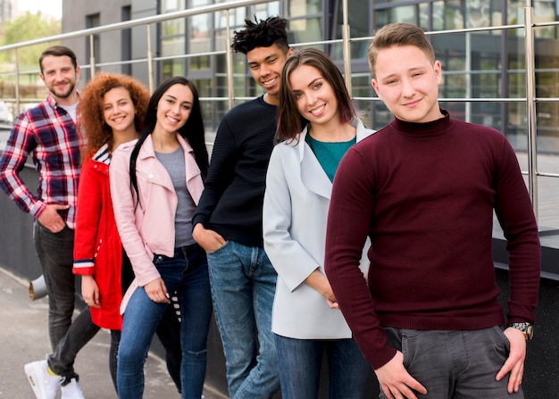 Portrait of happy multiracial friends looking at camera standing near railing