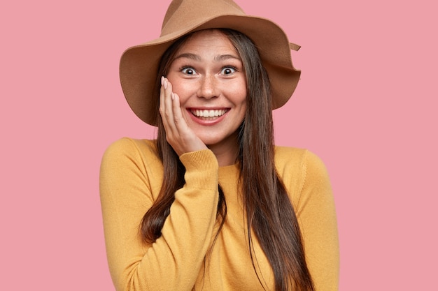 Portrait of happy overjoyed girl with appealing appearance, gazes with broad smile, has fun