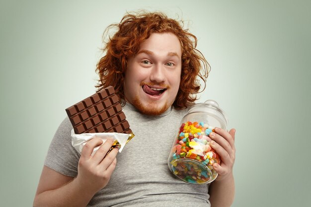 Portrait of happy plump young redhead bearded man looking at camera with cheerful expression