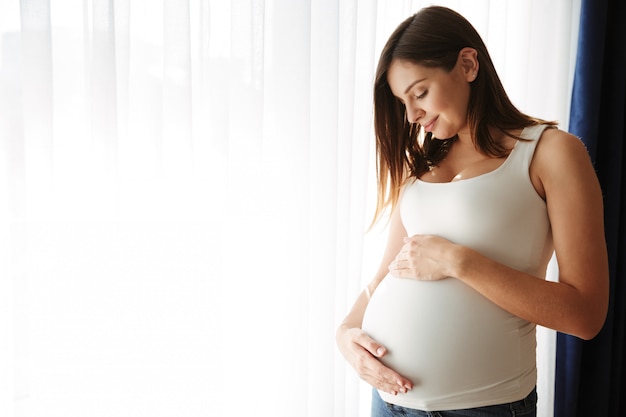 彼女の腹に触れる幸せな妊娠中の女性の肖像画