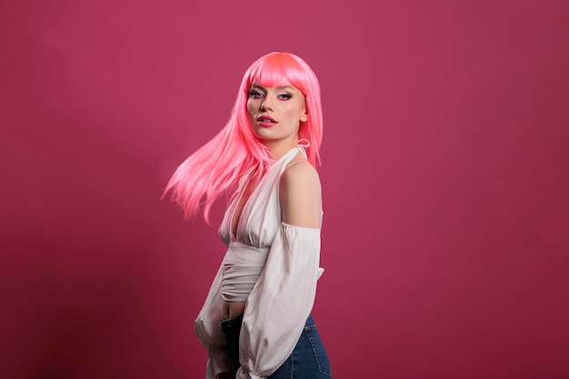 Portrait of happy pretty adult with cool makeup look and pink hair, looking at camera and feeling carefree. Female model with trendy fashion style looking elegant and atrractive in studio.