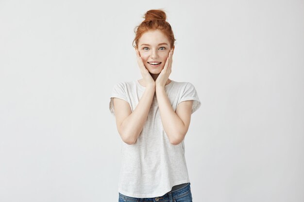 Portrait of happy redhead surprised woman with hands on cheeks.