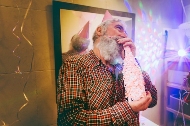 Portrait of a happy senior man enjoying the alcohol on birthday party