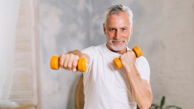 Portrait of happy senior man lifting weights