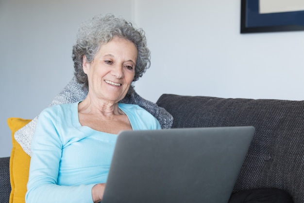 Portrait of happy senior woman using laptop at home