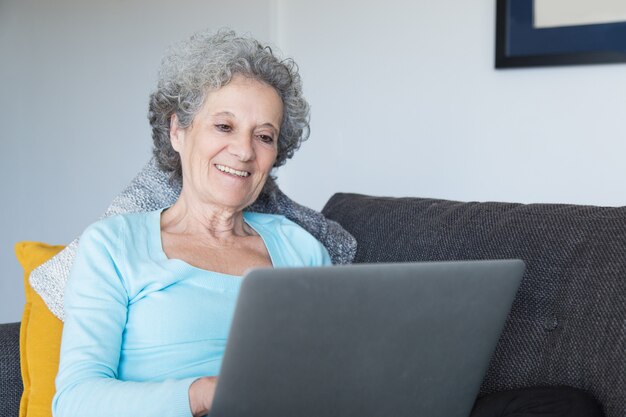 집에서 노트북을 사용하는 행복 한 고위 여자의 초상화