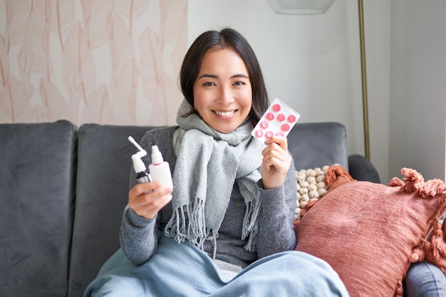 Free photo portrait of happy smiling asian girl showing medication sore throat spray and drugs from flu or cold