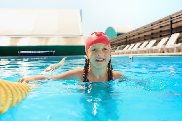 The portrait of happy smiling beautiful teen girl at the pool