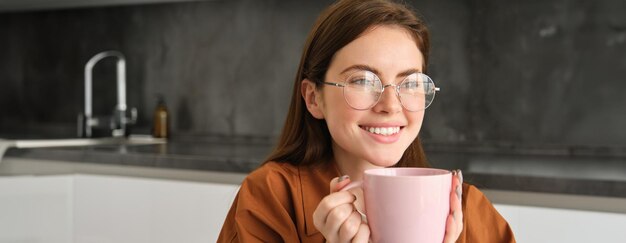 Free photo portrait of happy smiling woman relaxing with cup of tea girl enjoys delicious coffee smiles and