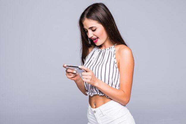 회색 배경에 고립 된 스마트 폰에 SMS를 입력하는 행복 한 웃는 여자의 초상화